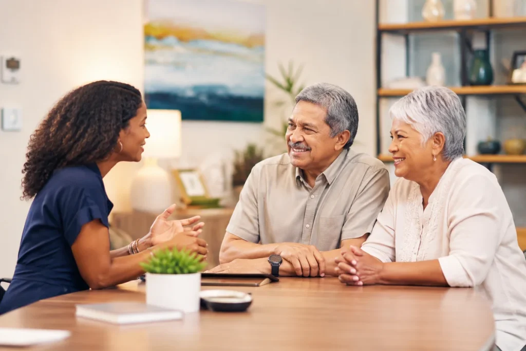 Travel advisor meeting with a smiling mature couple at a table, discussing trip ideas and bringing their travel plans to life